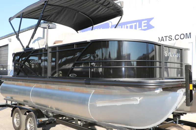 Slide: The Image of 2025 Sylvan Mirage X1 pontoon boat with black canopy on trailer. - 6