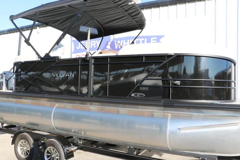 Slide: The Image of 2025 Sylvan Mirage X1 pontoon boat with black exterior and canopy, displayed on a trailer. - 10