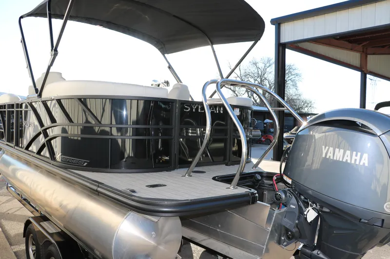 Slide: The Image of 2025 Sylvan Mirage X1 pontoon boat with Yamaha engine, docked outdoors. - 2