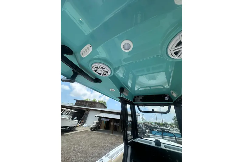Slide: The Image of 2026 Sportsman Open 232 Center Console boat interior with teal ceiling and speakers. - 19