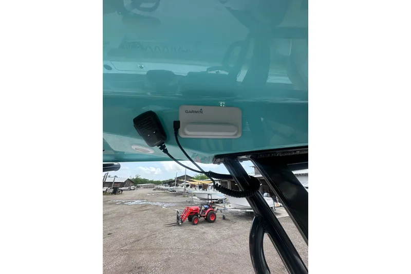 Slide: The Image of 2026 Sportsman Open 232 Center Console with Garmin equipment, docked near a red tractor. - 25