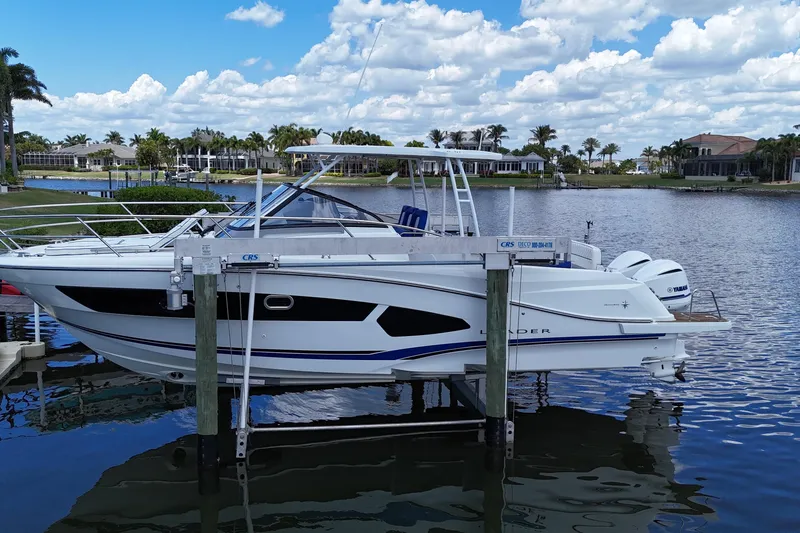 The Image of 2019 Jeanneau Leader 10.5 boat docked on a lift by a scenic waterfront. - 0