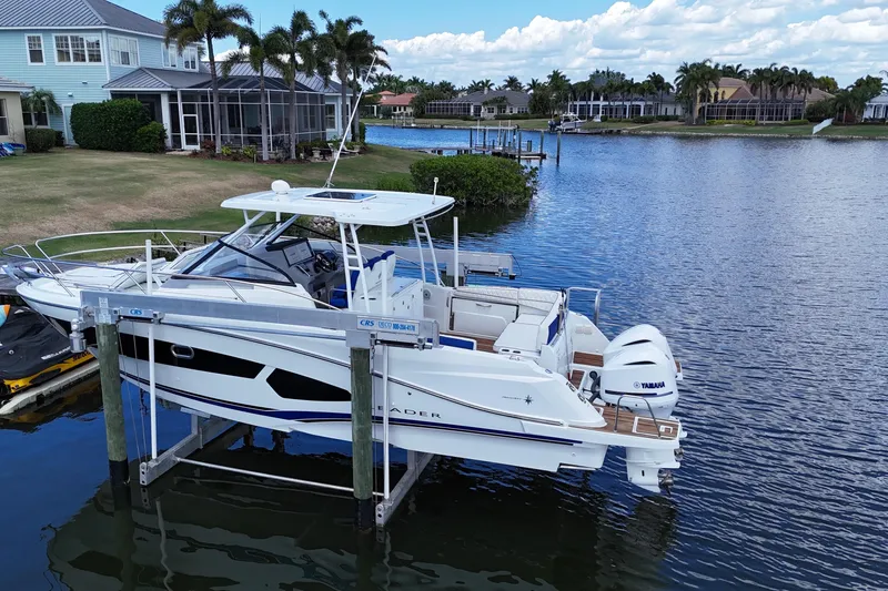 Slide: The Image of 2019 Jeanneau Leader 10.5 boat docked by waterfront homes, featuring twin Yamaha engines. - 13