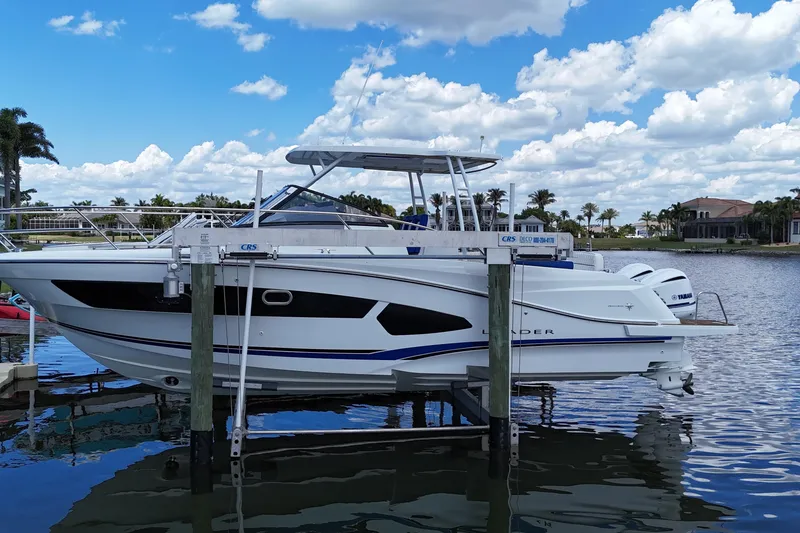 Slide: The Image of 2019 Jeanneau Leader 10.5 boat docked on a lift, under a partly cloudy sky. - 2