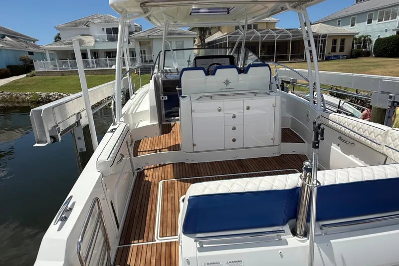 Slide: The Image of 2019 Jeanneau Leader 10.5 boat with spacious deck and seating, docked near waterfront homes. - 24