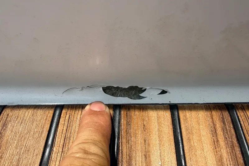 Slide: The Image of Damage on 2019 Jeanneau Leader 10.5 hull, with finger pointing for scale. - 27