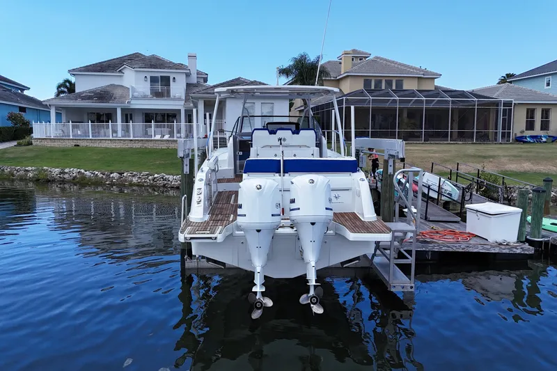 Slide: The Image of 2019 Jeanneau Leader 10.5 docked by waterfront homes, featuring dual outboard engines. - 4