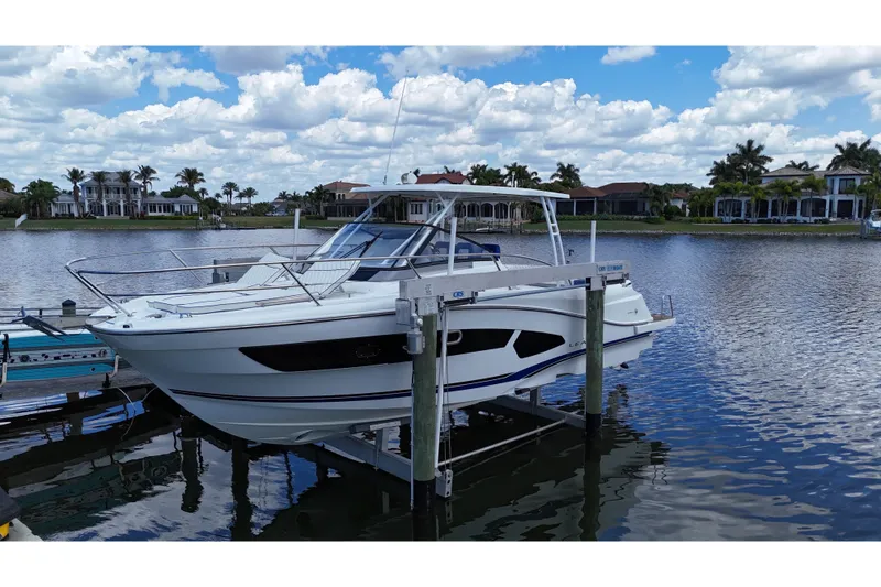 Slide: The Image of 2019 Jeanneau Leader 10.5 boat docked on a lift by waterfront homes. - 6