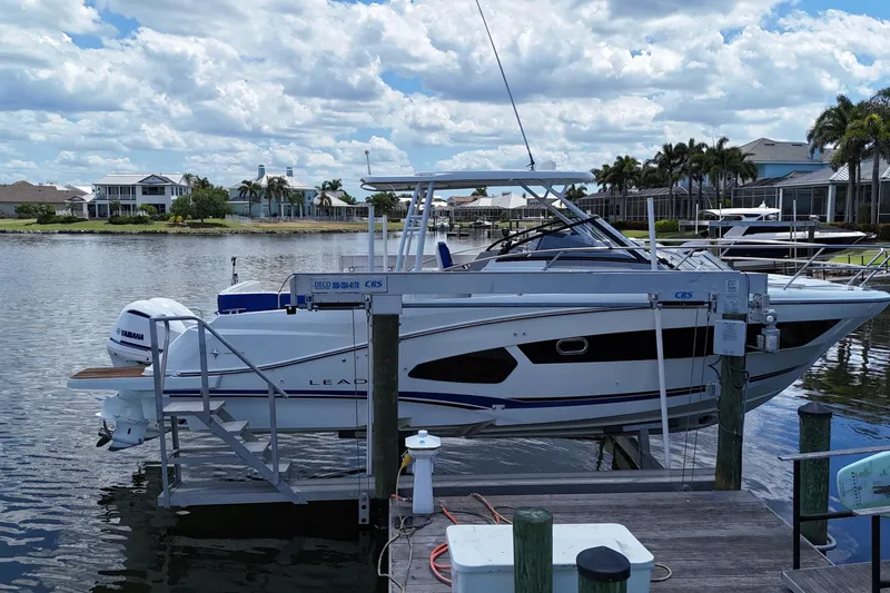 Slide: The Image of 2019 Jeanneau Leader 10.5 boat docked on a lift, with scenic waterfront background. - 7