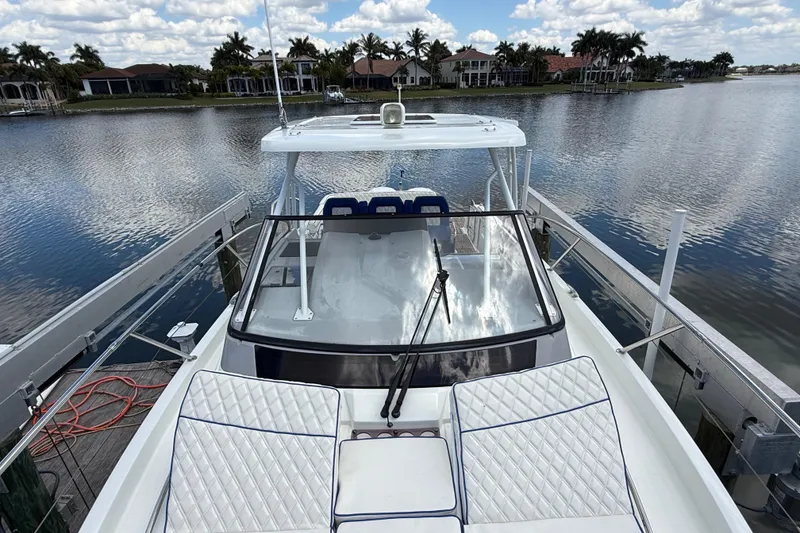 Slide: The Image of 2019 Jeanneau Leader 10.5 boat docked by a serene waterfront with luxury homes. - 99