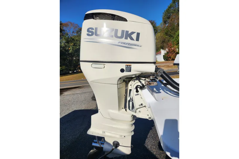 Slide: The Image of Suzuki outboard motor on 2011 C-Hawk 235 Center Console boat, parked outdoors. - 5