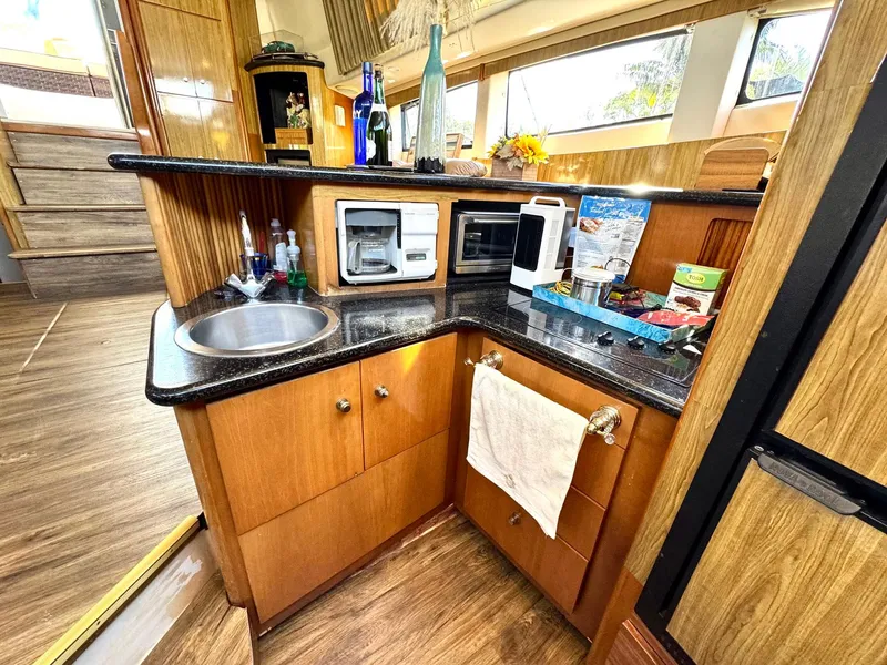 Slide: The Image of 2001 Carver 396 Motor Yacht kitchen with sink, microwave, and wooden cabinetry. - 14