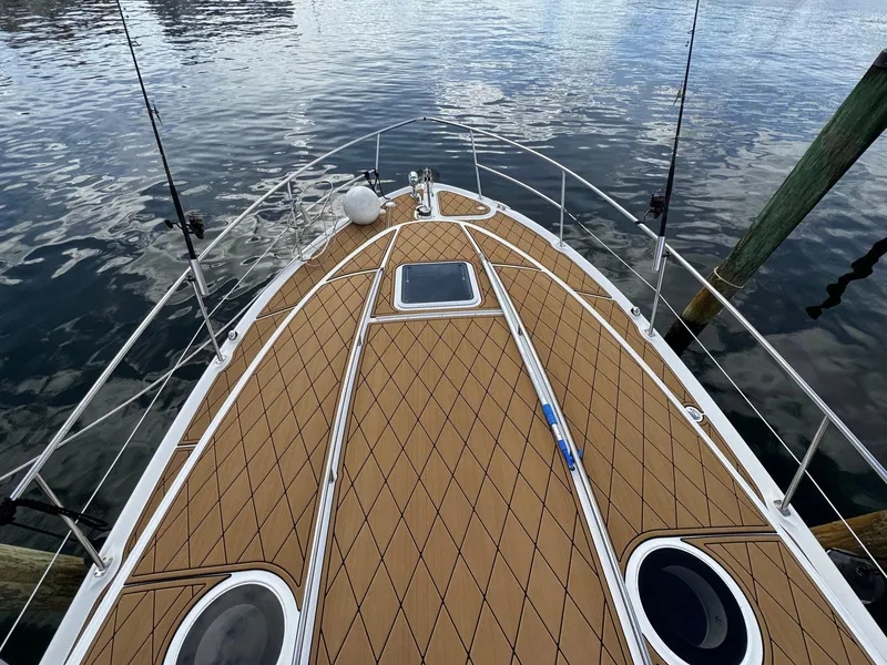 Slide: The Image of 2002 Sea Ray 360 Sundancer boat deck with teak flooring, docked on calm water. - 7