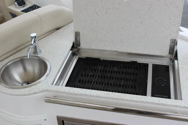 Slide: The Image of 2018 Regal 33 Express yacht kitchenette with sink and Kenyon grill. - 14
