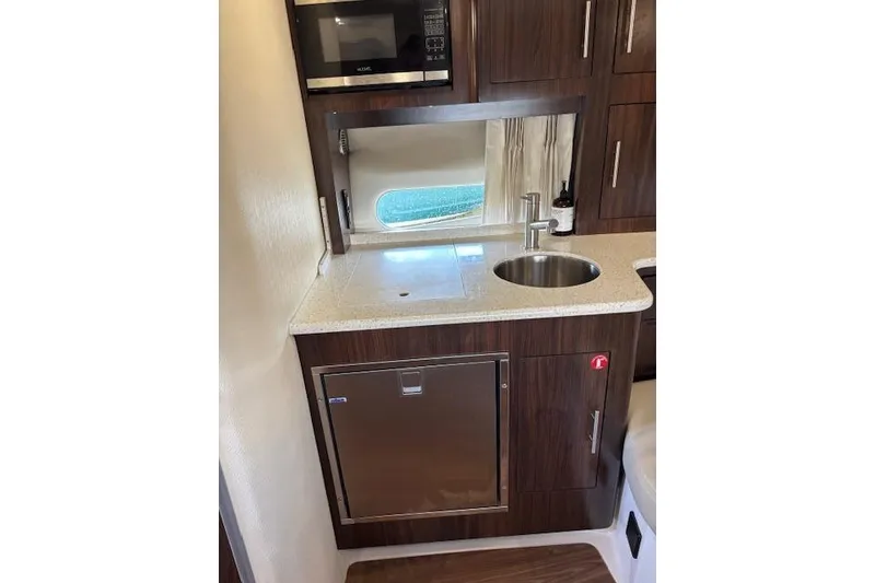 Slide: The Image of Compact kitchen area in a 2018 Regal 33 Express boat with sink and microwave. - 22