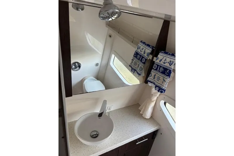 Slide: The Image of 2018 Regal 33 Express bathroom with modern sink, mirror, and nautical-themed towels. - 23