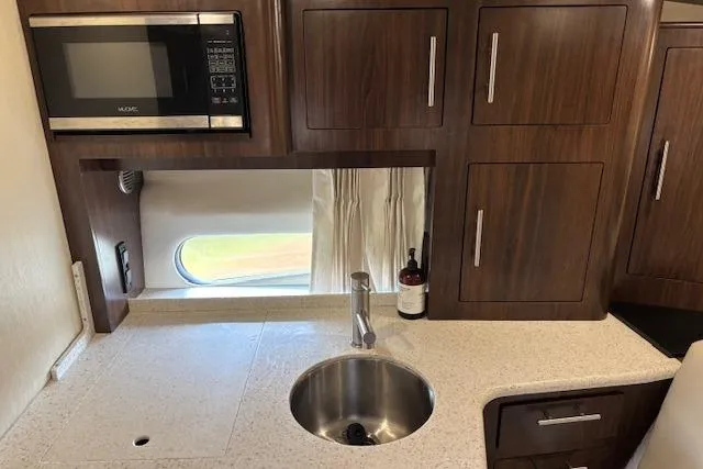 Slide: The Image of Compact kitchen area in a 2018 Regal 33 Express boat with microwave and sink. - 26