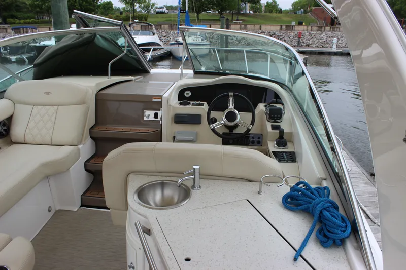 Slide: The Image of 2018 Regal 33 Express boat interior with helm, seating, and sink at marina. - 9