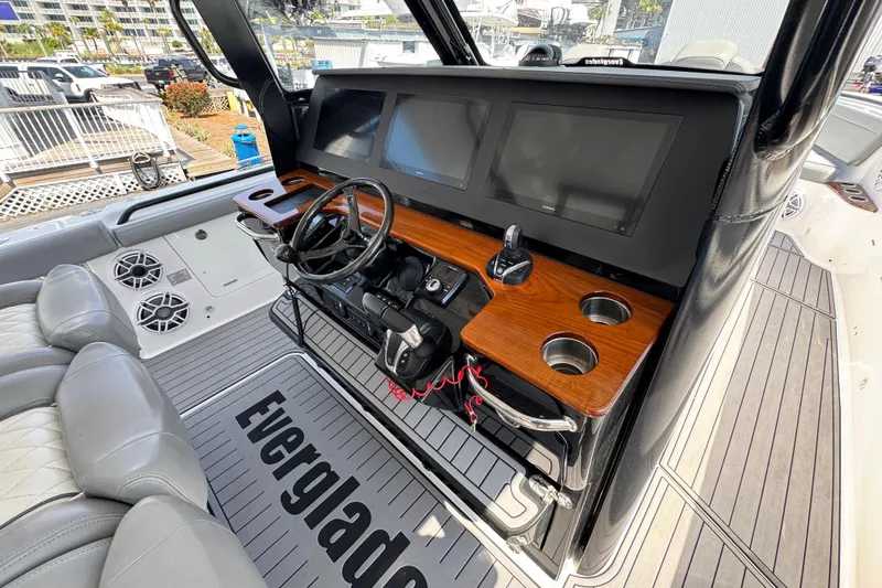 Slide: The Image of 2022 Everglades 395 Center Console boat dashboard with dual screens and wood accents. - 29