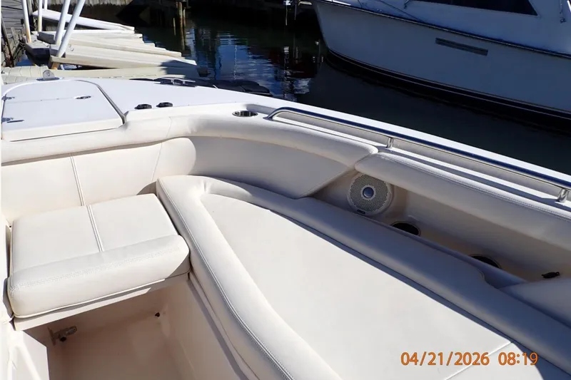 Slide: The Image of 2016 Grady-White Freedom 335 boat interior with white seating and speaker, docked by water. - 14