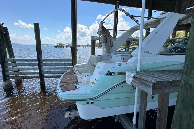 Slide: The Image of 2014 Monterey 260 Sport Yacht docked under a wooden shelter by the water. - 11