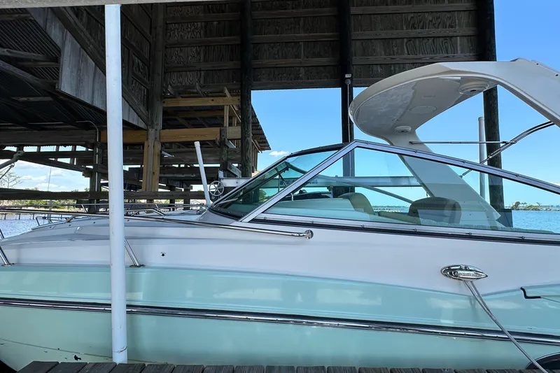 Slide: The Image of 2014 Monterey 260 Sport Yacht docked under a wooden shelter by the water. - 13