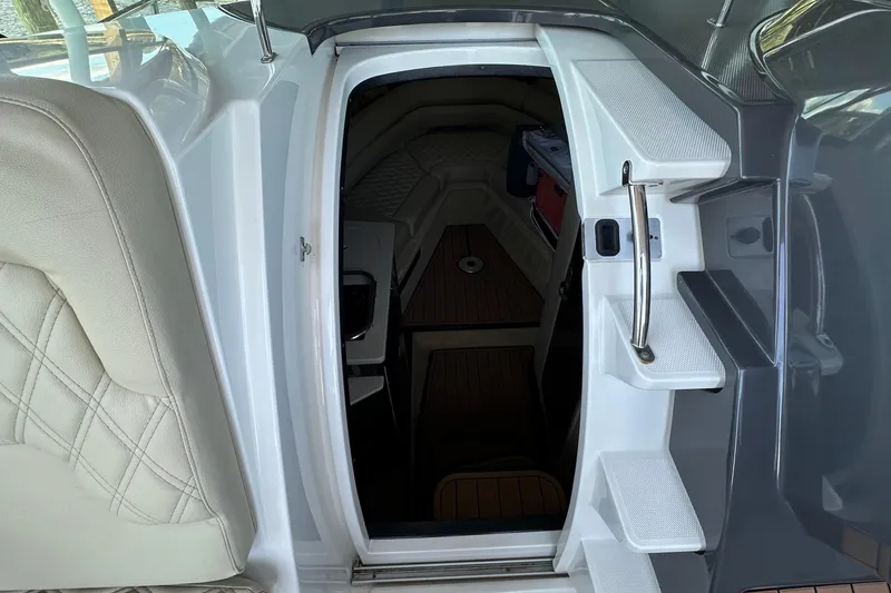 Slide: The Image of Interior cabin entrance of a 2014 Monterey 260 Sport Yacht with white seating and wooden flooring. - 24