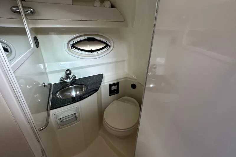 Slide: The Image of Compact bathroom in 2014 Monterey 260 Sport Yacht with sink, toilet, and porthole window. - 29