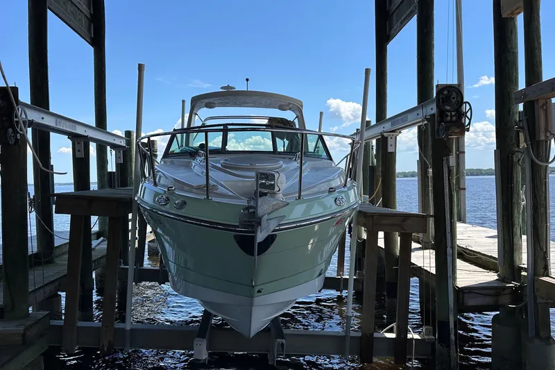 Slide: The Image of 2014 Monterey 260 Sport Yacht docked on a lift, with a scenic water backdrop. - 9