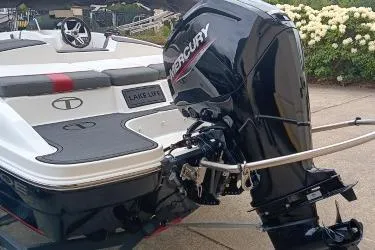 Slide: The Image of 2024 Tahoe T16 boat with Mercury outboard motor, docked near blooming flowers. - 7