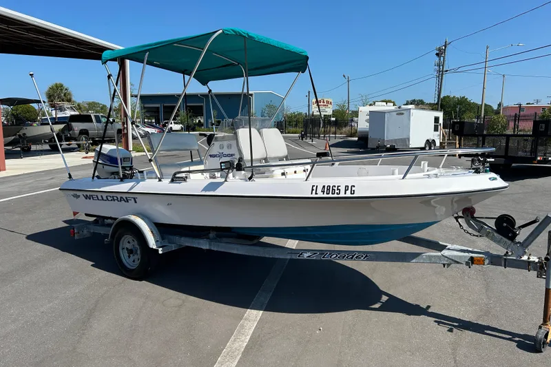 The Image of 1996 Wellcraft 160 Fisherman boat on trailer with canopy in parking lot. - 1