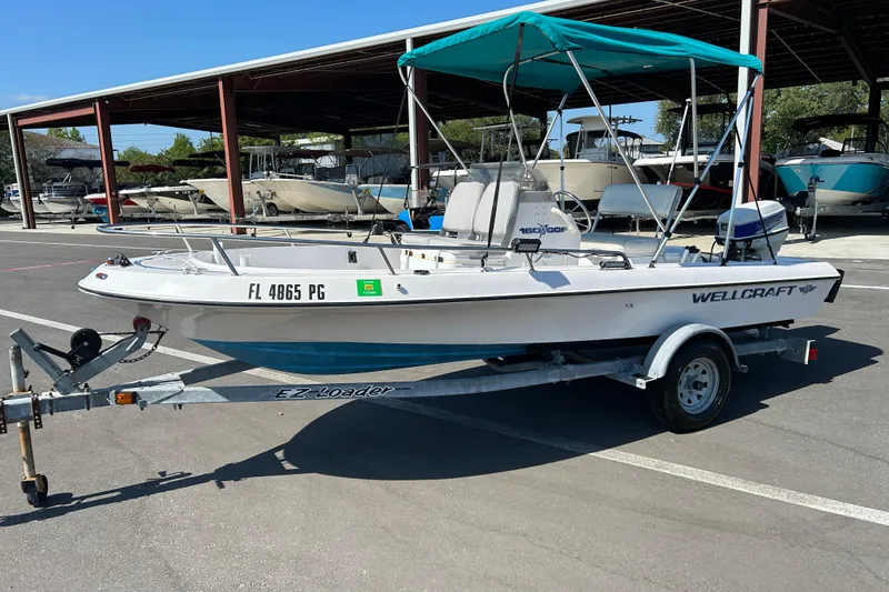 Slide: The Image of 1996 Wellcraft 160 Fisherman boat on trailer with teal canopy in marina parking lot. - 5