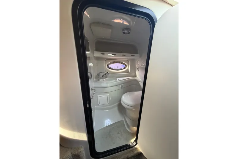 Slide: The Image of 2020 Crownline 286 SC boat bathroom interior with sink, toilet, and porthole window. - 18