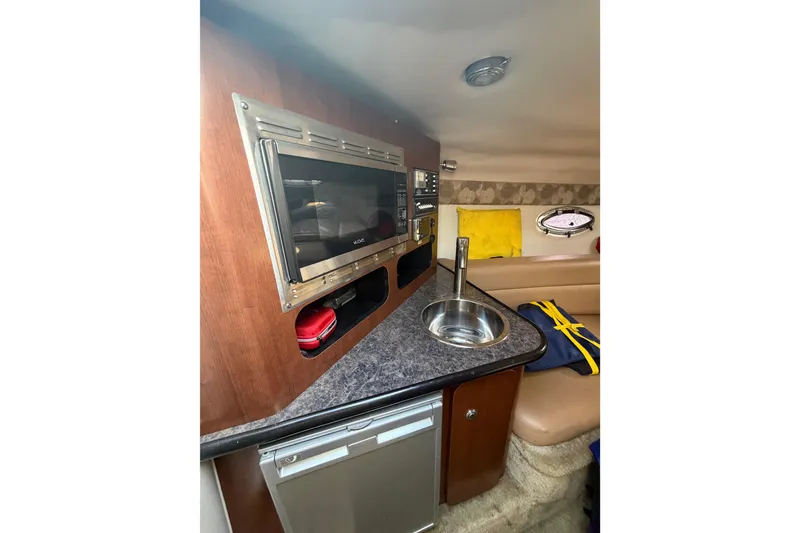 Slide: The Image of 2020 Crownline 286 SC cabin interior with kitchenette, microwave, sink, and seating area. - 19