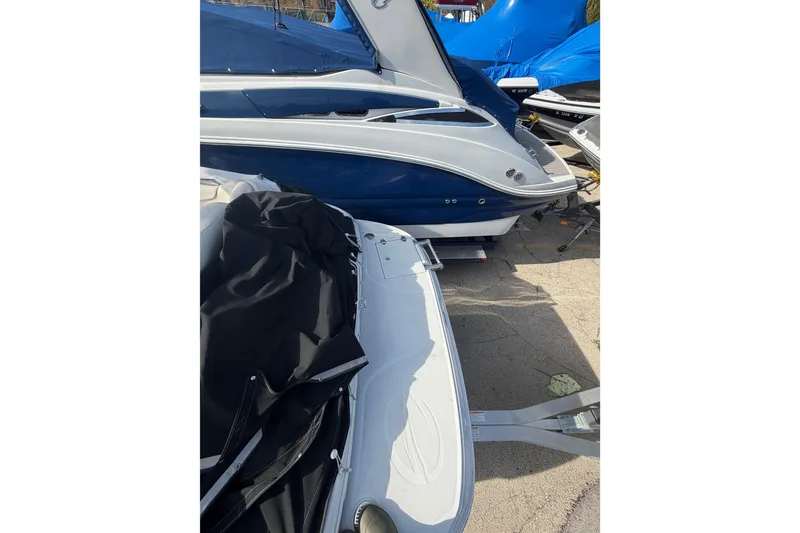 Slide: The Image of 2020 Crownline 286 SC boat with blue and white exterior, parked on a trailer. - 8
