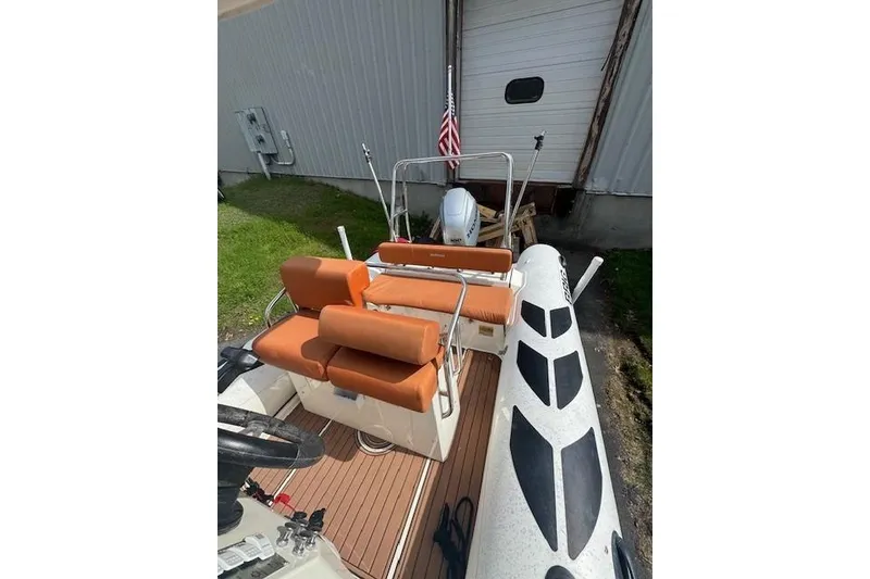 Slide: The Image of 2019 Brig Navigator 570 boat with orange seating and American flag, docked near a building. - 7