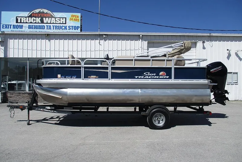 The Image of 2023 Sun Tracker Bass Buggy 18 DLX pontoon boat on trailer, parked outside truck wash. - 1