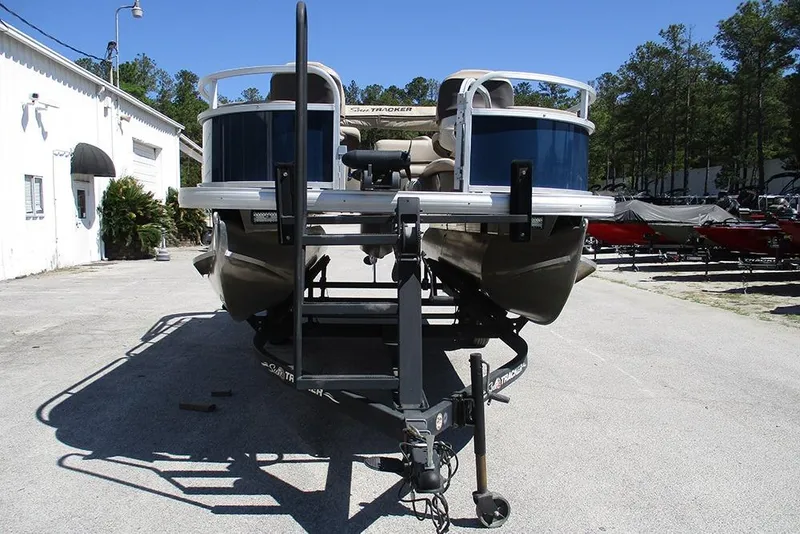 Slide: The Image of 2023 Sun Tracker Bass Buggy 18 DLX pontoon boat on trailer, parked outdoors. - 4