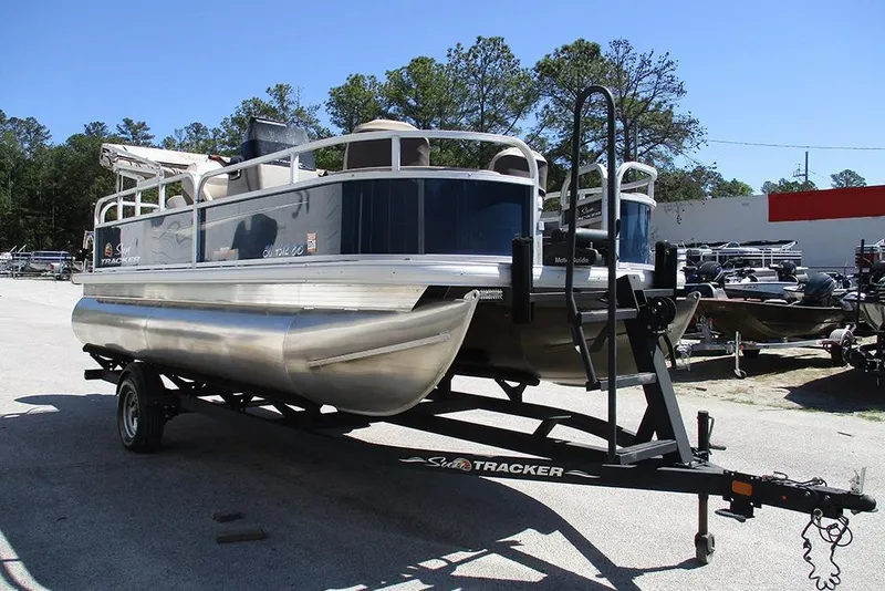 Slide: The Image of 2023 Sun Tracker Bass Buggy 18 DLX pontoon boat on trailer in outdoor setting. - 5