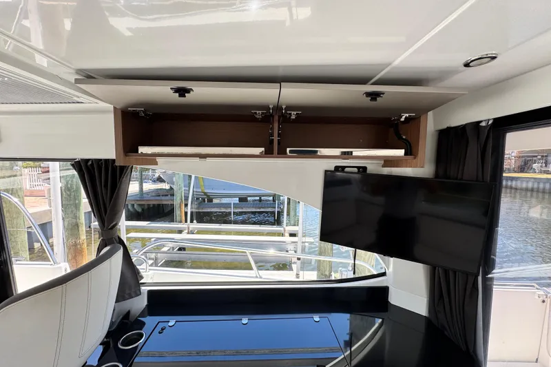 Slide: The Image of Interior of 2021 Beneteau Antares 11 with open cabinet and mounted TV. - 23