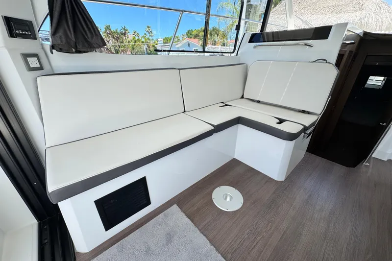 Slide: The Image of Interior seating area of 2021 Beneteau Antares 11 boat, featuring modern white cushions. - 24