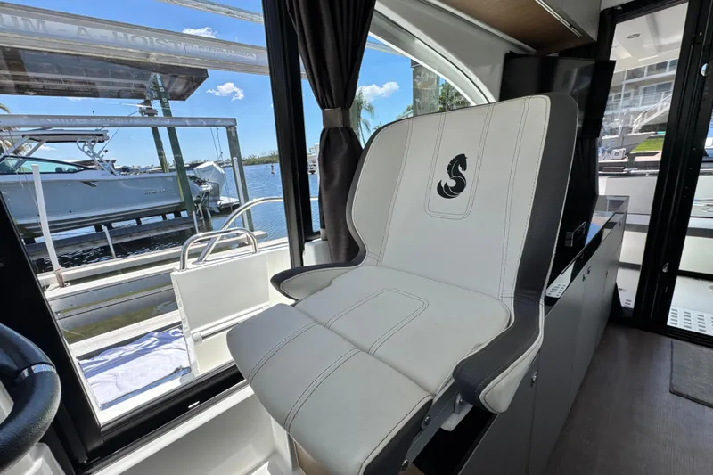 Slide: The Image of 2021 Beneteau Antares 11 interior with stylish captain's chair and marina view. - 31