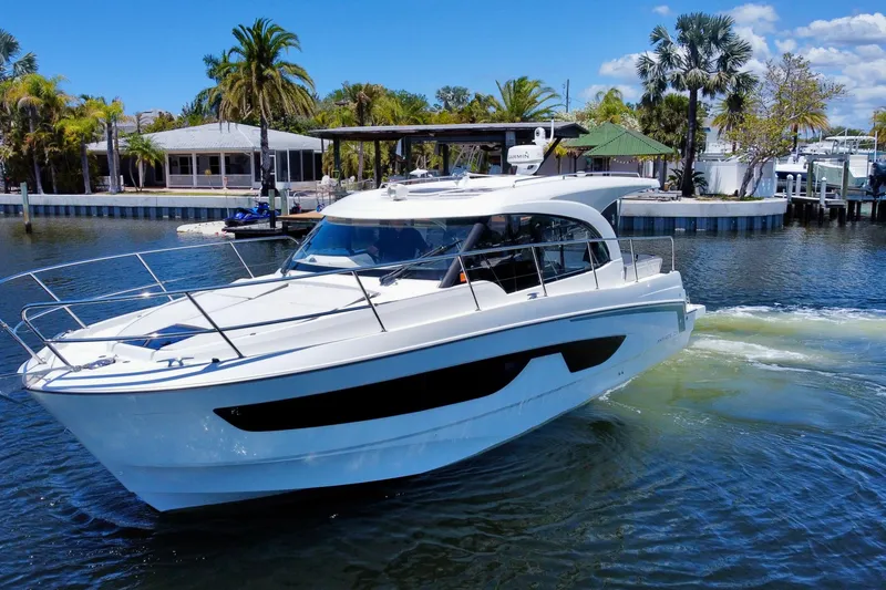 Slide: The Image of 2021 Beneteau Antares 11 cruising in a scenic waterfront setting with palm trees. - 8