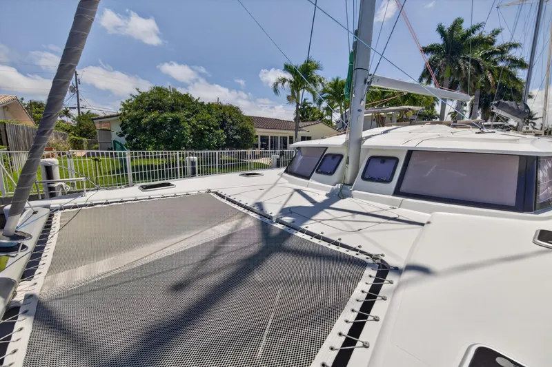 Slide: The Image of 2015 Fountaine Pajot Helia 44 catamaran with spacious deck and netting, docked near lush greenery. - 37