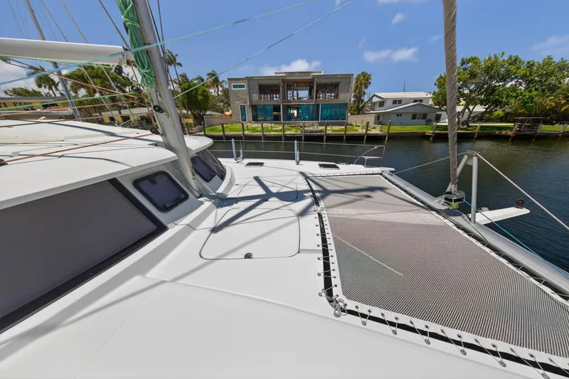 Slide: The Image of 2015 Fountaine Pajot Helia 44 catamaran docked by waterfront homes, sunny day. - 44