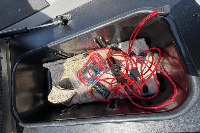 Slide: The Image of Storage compartment in a 2025 Skeeter ZXR21 boat with red cords and towel. - 15
