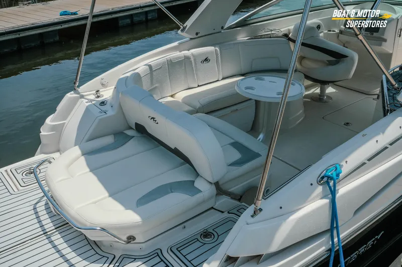 Slide: The Image of 2012 Monterey 264FS boat interior with white seating and table, docked by the water. - 12