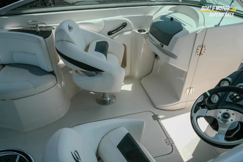 Slide: The Image of Interior of a 2012 Monterey 264FS boat featuring white seating and steering console. - 16