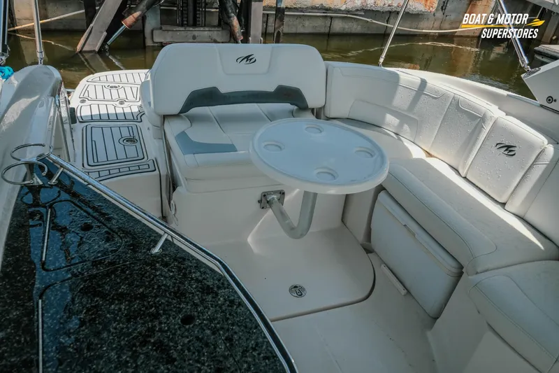 Slide: The Image of 2012 Monterey 264FS boat interior with seating and table, docked by the water. - 19