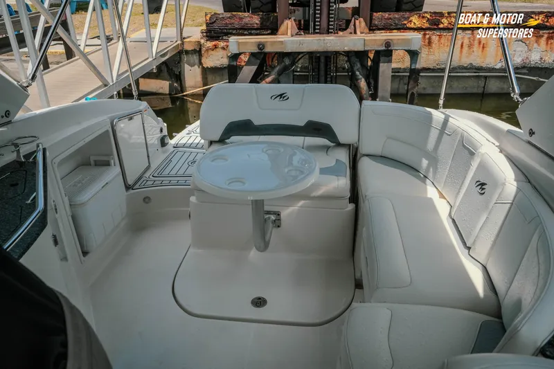 Slide: The Image of 2012 Monterey 264FS boat interior with white seating and table at dock. - 33